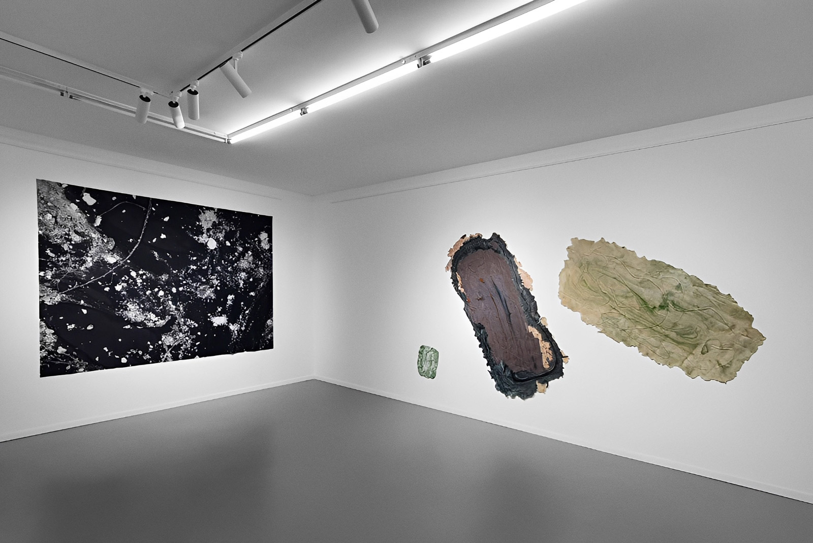 Exhibition view of “Is History OK?” by Johannes Hugo Stoll, showing a large black-and-white work on the left wall and three abstract works arranged across the adjacent white wall.
